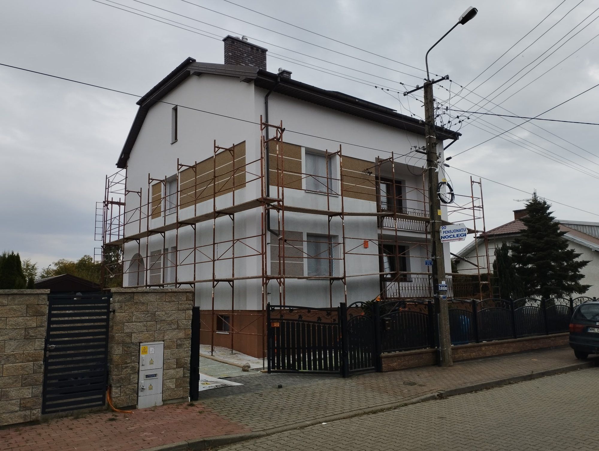 Piętrowy dom na rusztowaniach w trakcie docieplania ścian